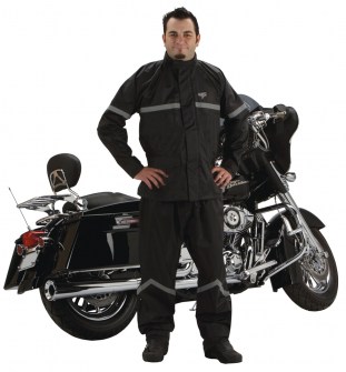 Photo of man wearing StormRider rainsuit in black standing next to motorcycle