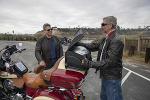 Photo of Weekender on trunk of Indian Motorcycle, one man removing helmet from bag